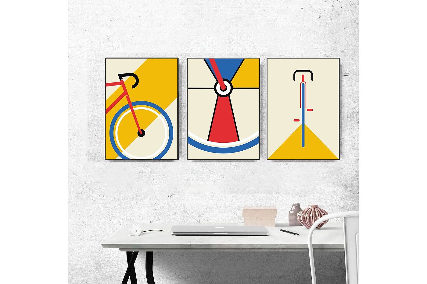 Dreiteiliges Poster mit Fahrradmotiven an einer grauen Wand mit Schreibtisch davor. 