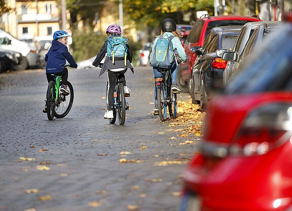 Drei Mädchen mit dem Rad auf dem Weg zur Schule. 